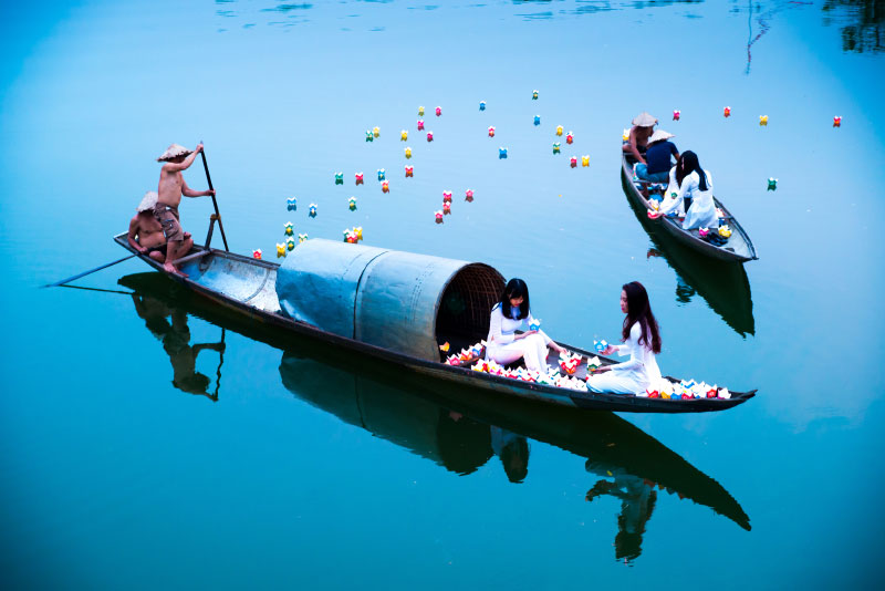 Vietnamese girls wearing traditional Ao Dai light floating lanterns on the Perfume River